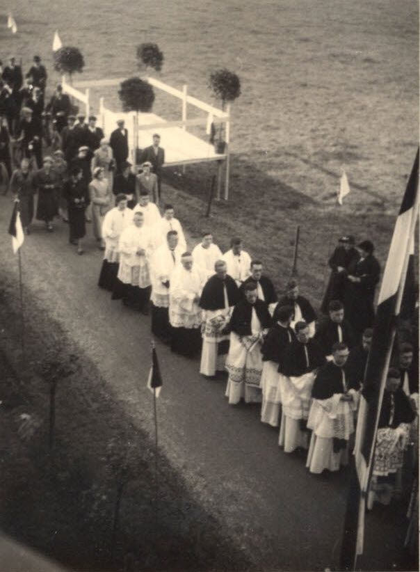 foto vanaf hoogte op een stoet kruisheren in liturgische kleding lopend over straat in een plechtige optocht