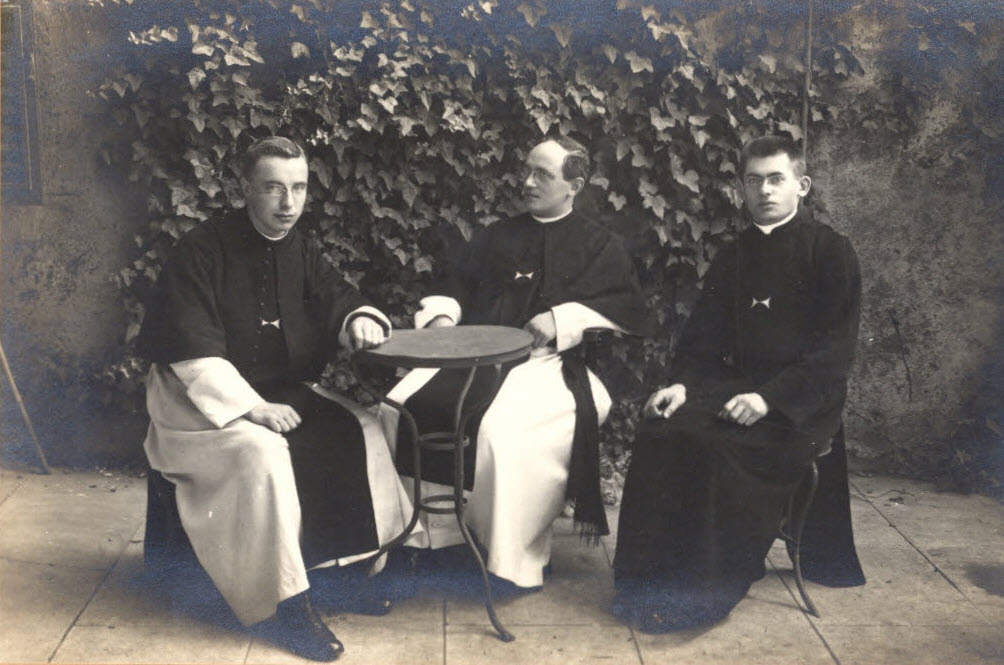 drie kruisheren in habijt gezeten rond een terrastafeltje