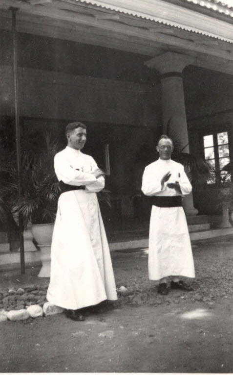 Foto van twee kruisheren in tropenhabijt voor een veranda.