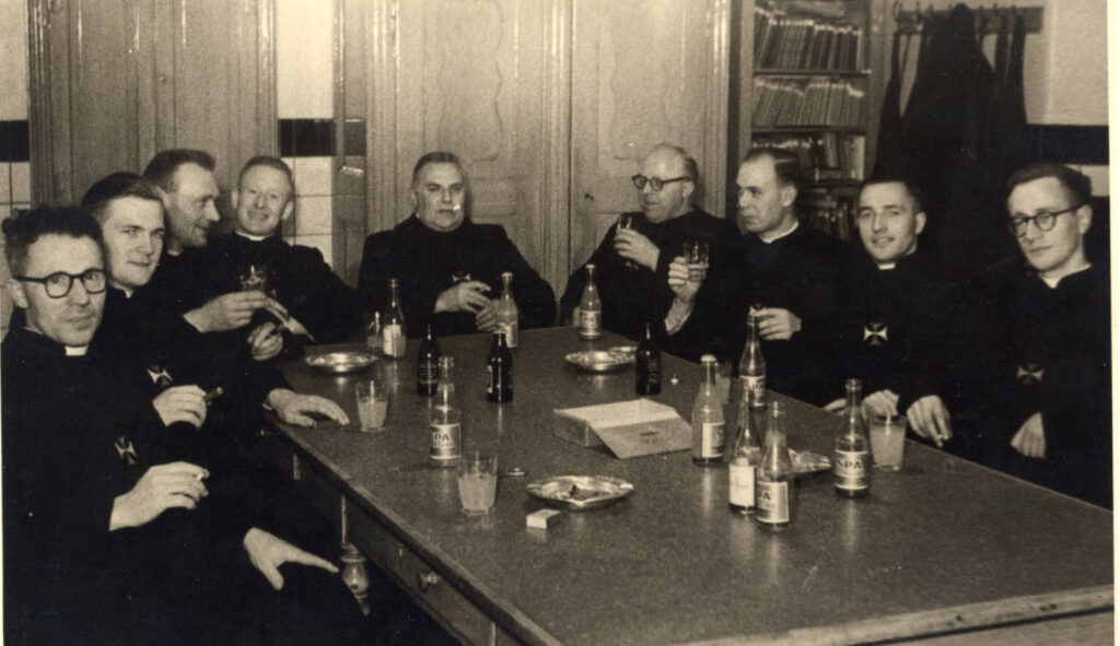 groep kruisheren in broederhabijt in recreatie rond een tafel gezeten