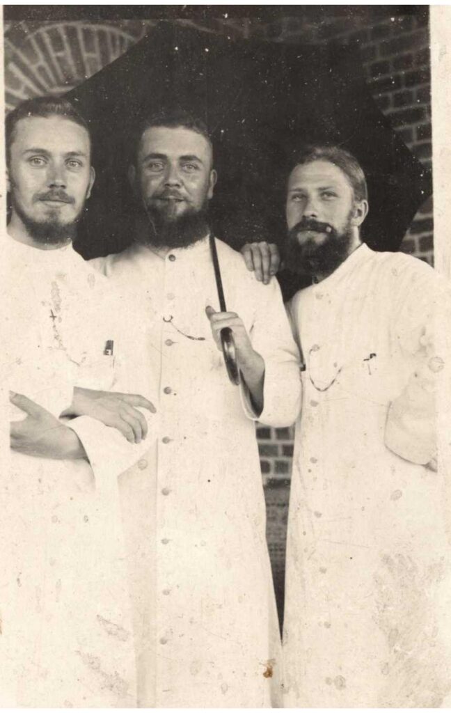 drie missionarissen met baard in witte toog, en één uitgeklapte paraplu