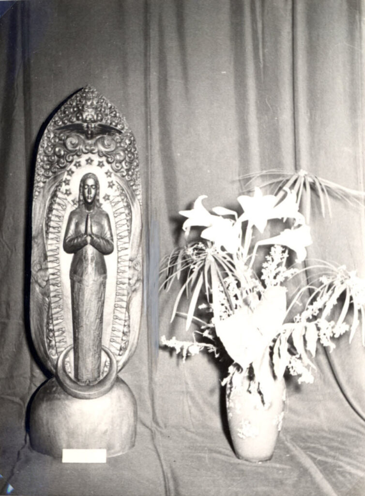 Vrijstaande beeltenis van Maria in reliëf met daarnaast ter devotie een vaas met bloemen
