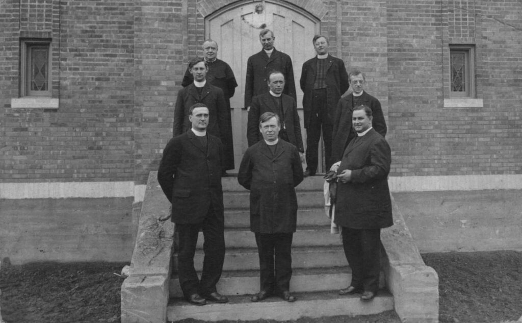 groep van 9 clerici en kruisheren in clergy op de treden voor een kerkdeur
